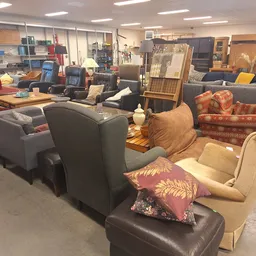 Winkelinterieur met diverse tweedehands meubels, fauteuils en banken uitgestald op de vloer