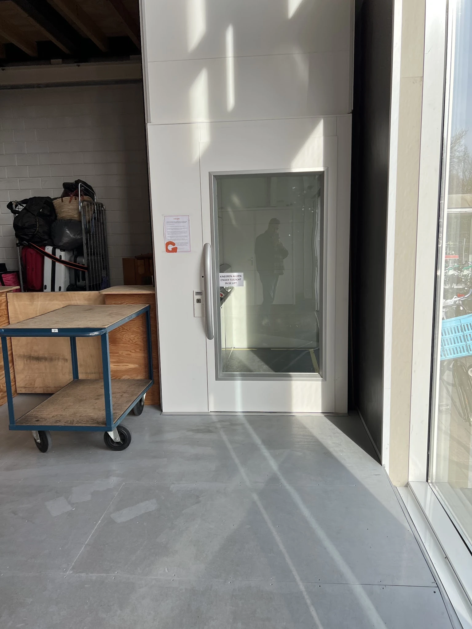Winkelinterieur met houten tafel op wielen, glazen deur en stellingen met spullen op de achtergrond