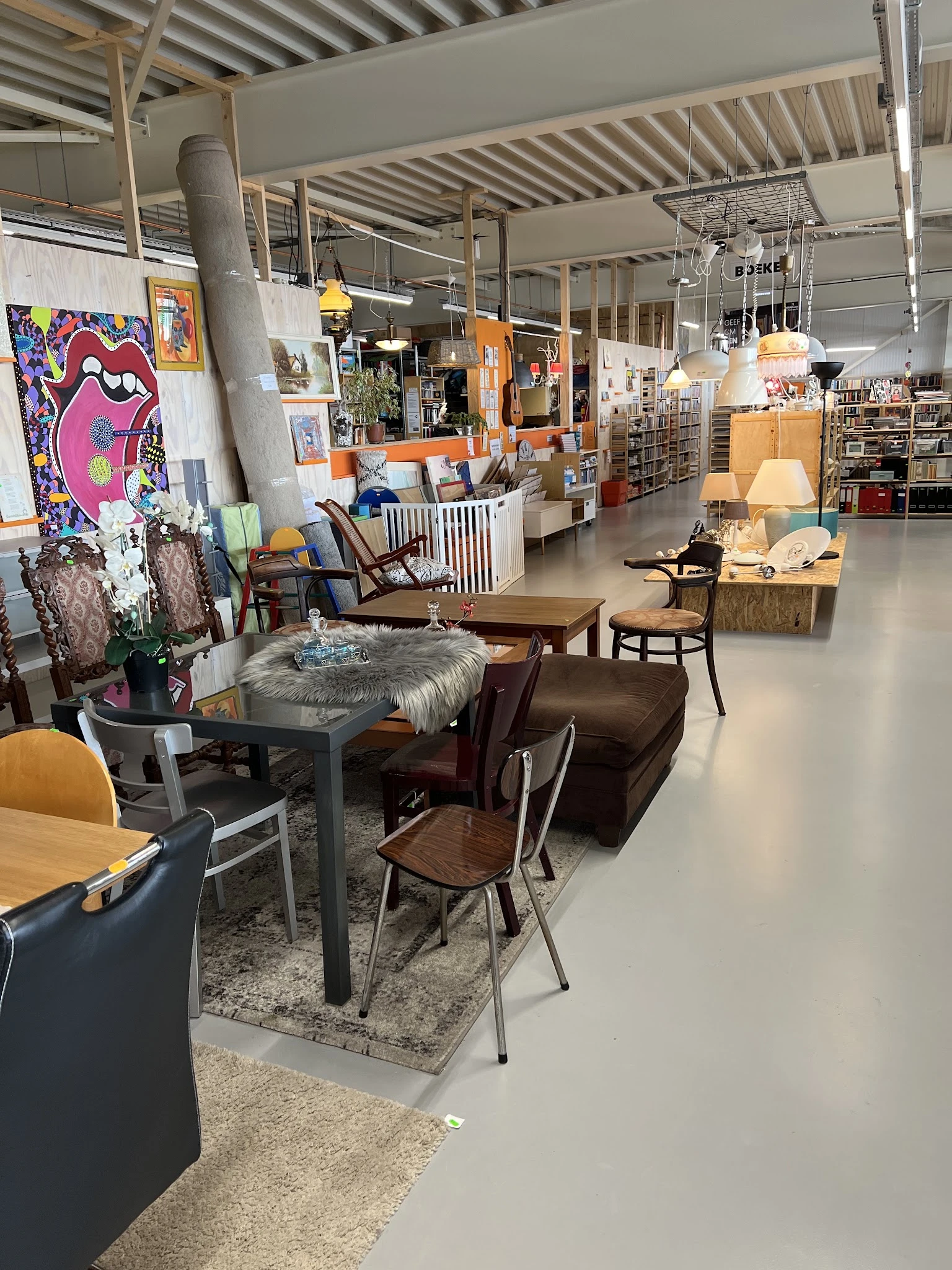 Winkelvloer met meubels en inrichtingsartikelen, waaronder stoelen, tafels, lampen en kunstwerken aan de muur
