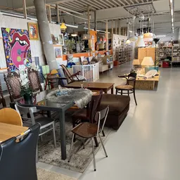 Winkelvloer met meubels en inrichtingsartikelen, waaronder stoelen, tafels, lampen en kunstwerken aan de muur