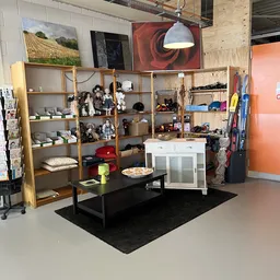 Winkelvloer met houten stellingkasten, zwarte tafel en diverse tweedehands artikelen in een kringloopwinkel
