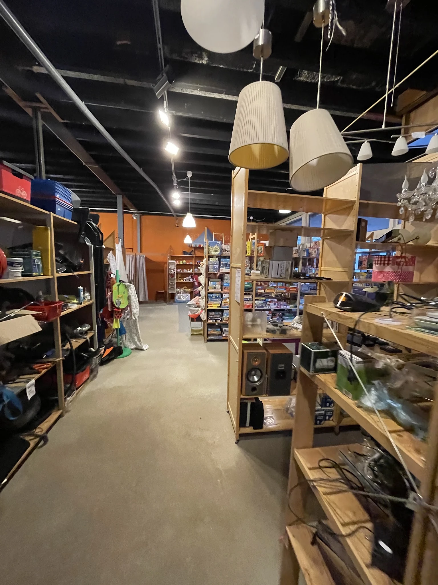 Overzicht van de winkelvloer met houten stellingen, diverse artikelen en producten, oranje muur op achtergrond