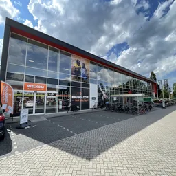 Moderne gevel van kringloopwinkel met grote glazen pui, welkomstteken en ingang aan de Peizerweg