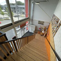 Trap met houten treden naar beneden in het trappenhuis van de winkel met ramen en inbouwkasten