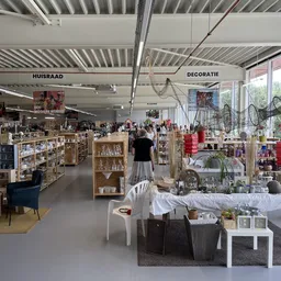 Winkelvloer met stellingen, rekken en uitgestalde spullen in een kringloopwinkel met duidelijke afdelingen