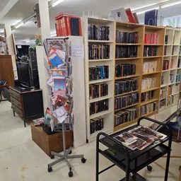 Binnenaanzicht van kringloopwinkel met houten boekenkast, dvd-rekken en displays met merchandise