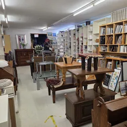 Winkelvloer met boekenkasten, houten meubelen en diversen huisraad in kringloopwinkel