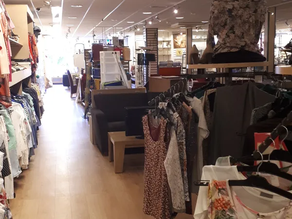 Winkelvloer met kledingrekken, stellingen en spullen in een kringloopwinkel