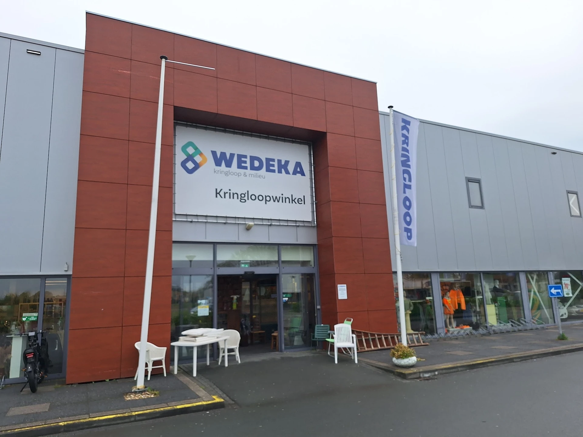 Voorgevel van kringloopwinkel met rood metselwerk en groot WEDEKA-logo met tekst Kringloopwinkel