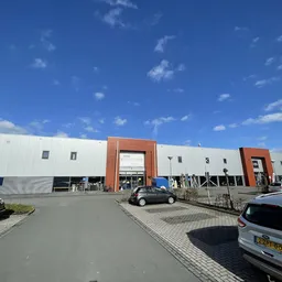Exterieur van kringloopwinkel Wedeka met wit gebouw, oranje accenten en parkeerplaats