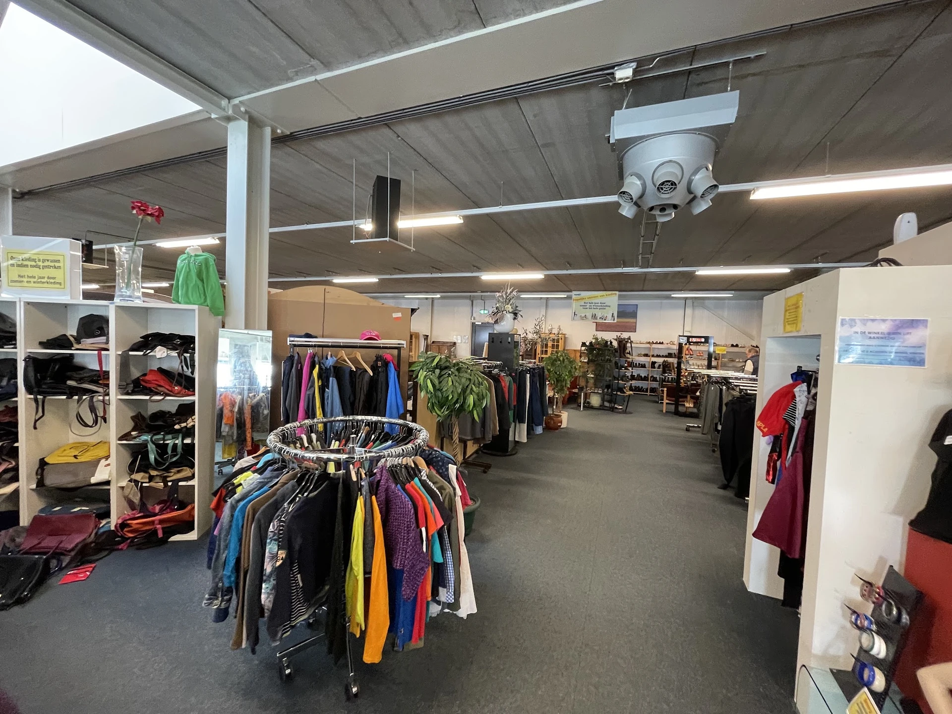 Winkelvloer met kledingrekken en stellingen vol tweedehands kleding en accessoires