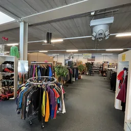 Winkelvloer met kledingrekken en stellingen vol tweedehands kleding en accessoires