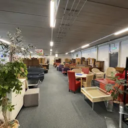 Ruim winkelbinnenland met diverse meubels, stoelen en huisraad uitgestald onder ledverlichting