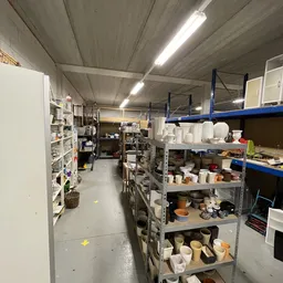 Winkelinterieur met stellingen vol huishoudelijke artikelen, potten en serviesgoed in kringloopwinkel