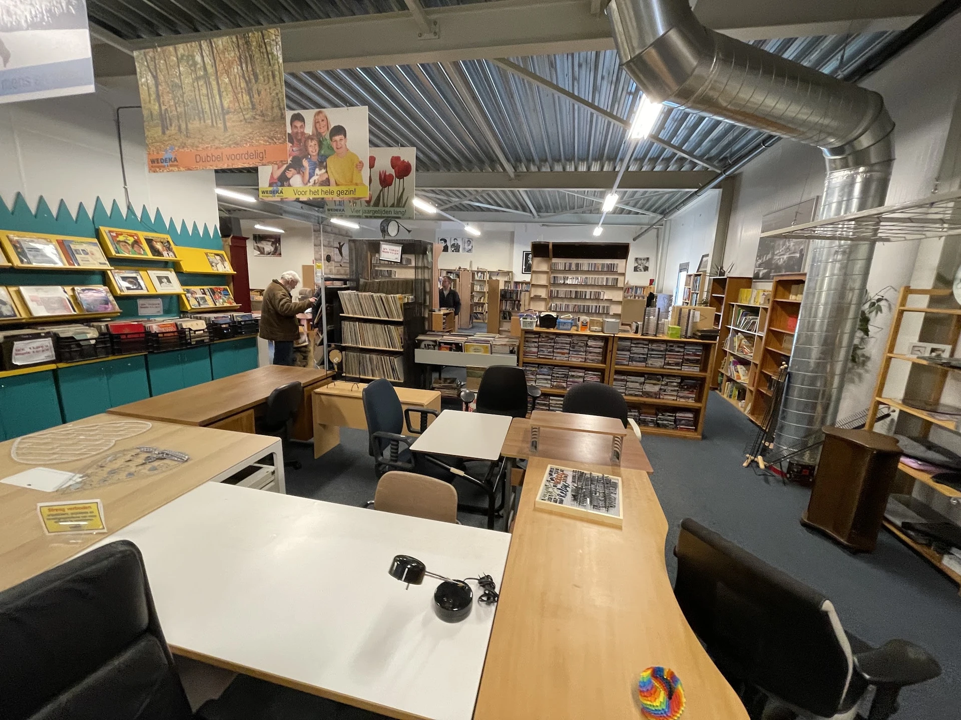 Werkruimte met tafels, stoelen en boekenrekken vol tweedehands boeken in een kringloopwinkel