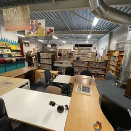 Werkruimte met tafels, stoelen en boekenrekken vol tweedehands boeken in een kringloopwinkel