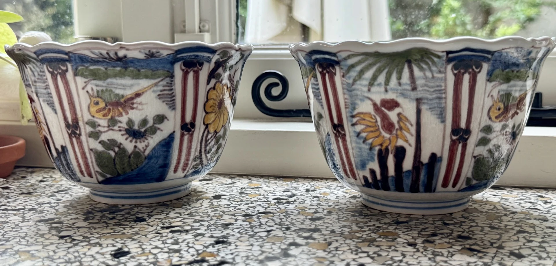 Twee decoratieve porseleinen kannen met blauw-wit patroon en bloemmotieven op een granito werkblad.
