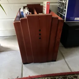 Roodbruin/terracottakleurig meubelstuk, mogelijk een kast of dressoir, met verticale lijnen en kleine zwarte knoppen