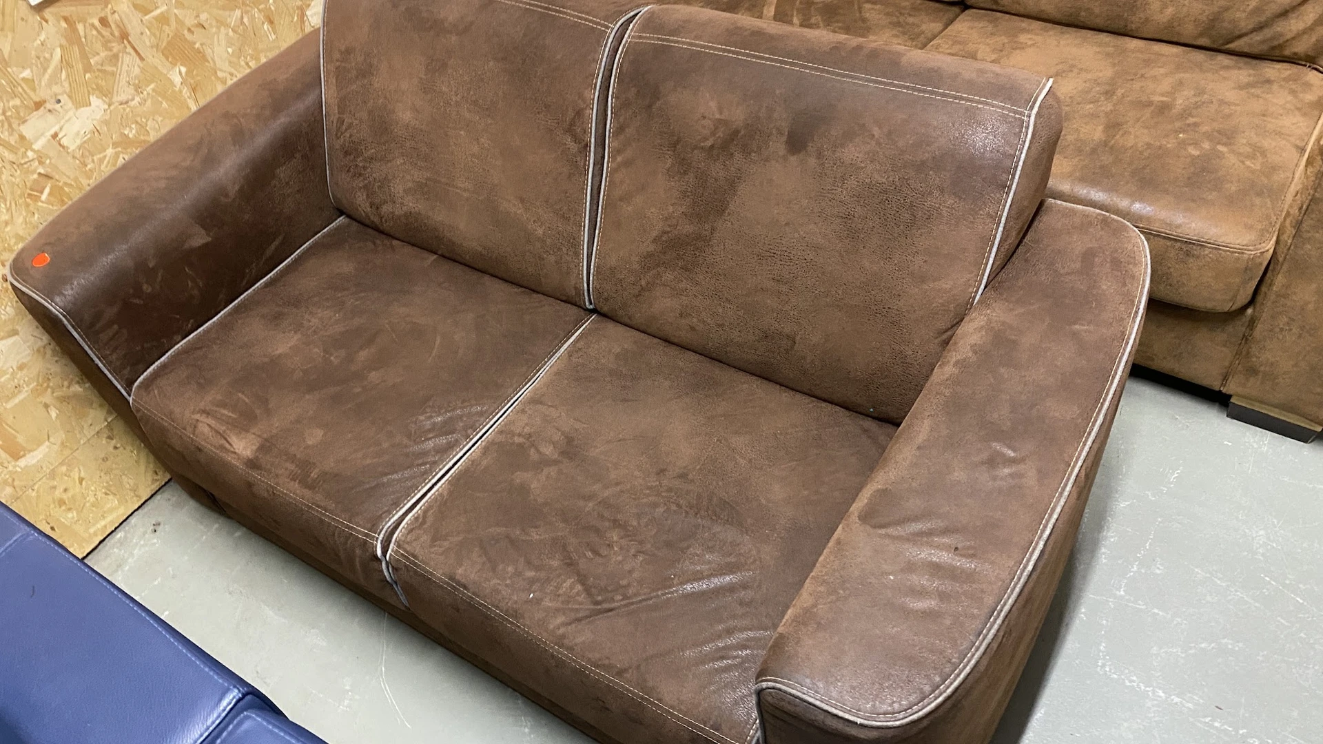 Tweedehands bruine suède fauteuil met twee zitplaatsen en witte stiksels
