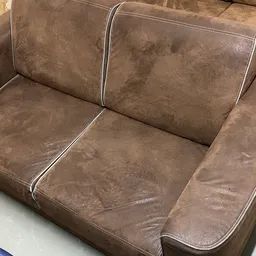 Tweedehands bruine suède fauteuil met twee zitplaatsen en witte stiksels