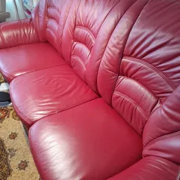 Close-up van een roze/rood lederen fauteuil met geplooide rugleuning