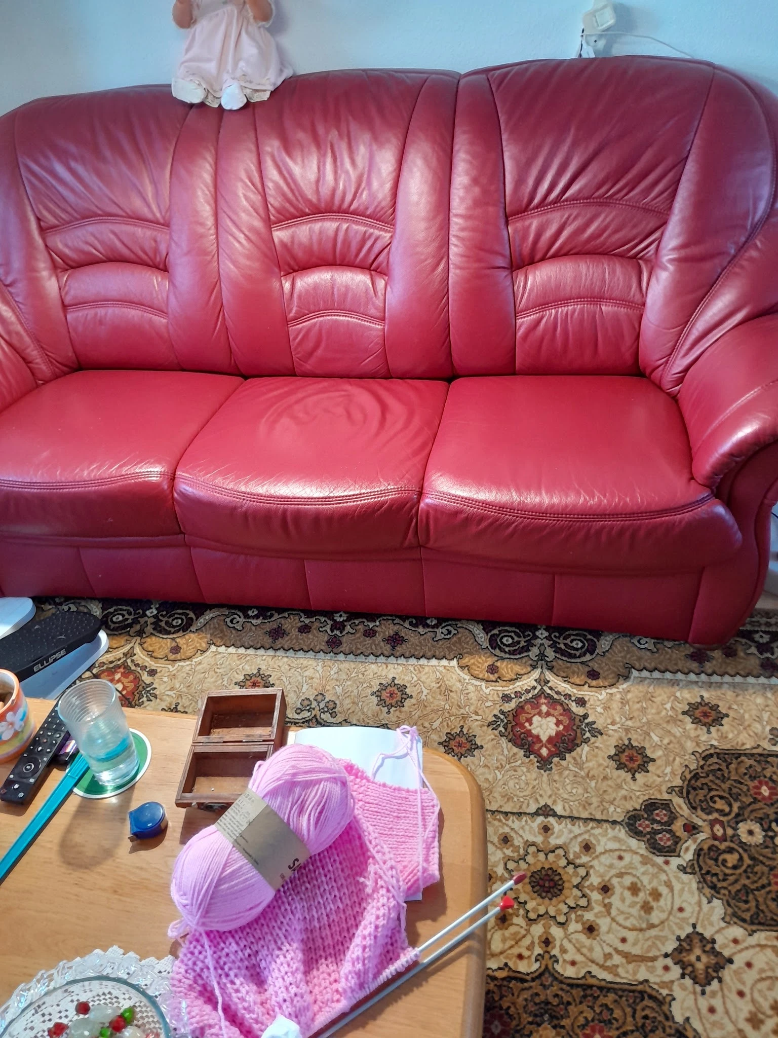 Roze lederen driezitsbank in een woonkamer met gemusterd tapijt