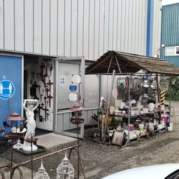 Exterieur van kringloopwinkel met blauwe deur en stellingen met spullen buiten