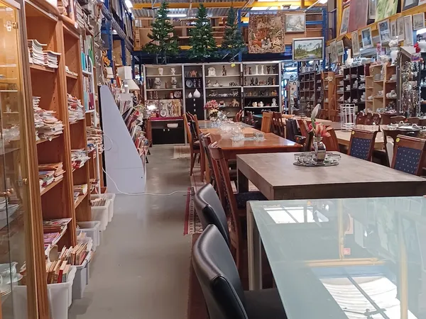 Winkelvloer van kringloopwinkel met houten meubels, vitrines en stellingen vol spullen