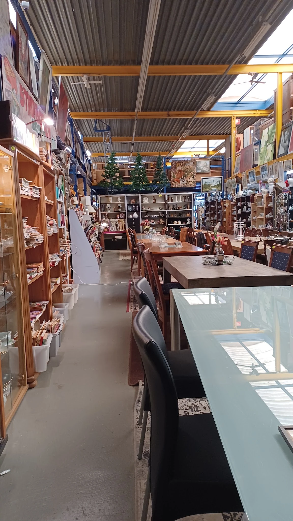 Winkelvloer van kringloopwinkel met houten meubels, vitrines en stellingen vol spullen