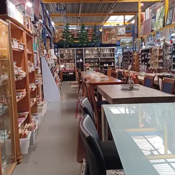 Winkelvloer van kringloopwinkel met houten meubels, vitrines en stellingen vol spullen