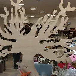 Winkelvloer met decoratief kunstwerk van witte takken aan muur en diverse spullen in kringloopwinkel