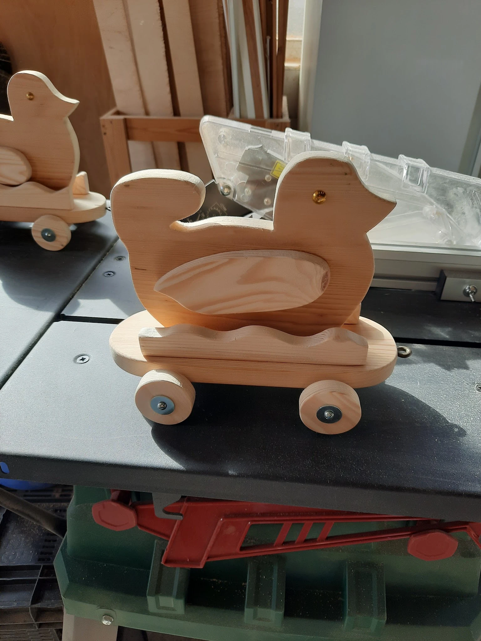 Houten speelgoedwagen in de vorm van een eend met wielen, op een donker bureau