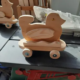 Houten speelgoedwagen in de vorm van een eend met wielen, op een donker bureau
