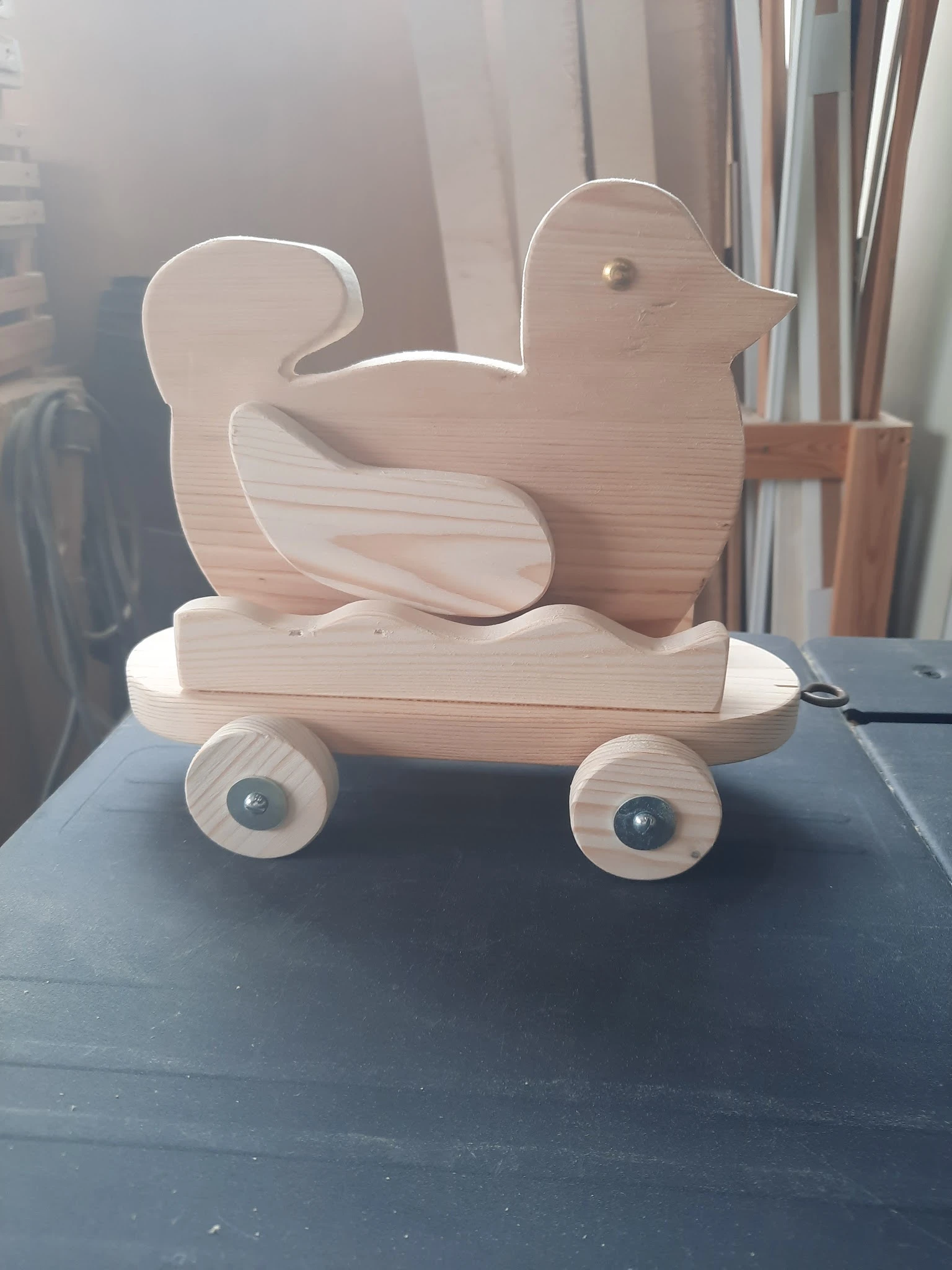 Houten speelgoed in de vorm van een eend op wielen, gemaakt van naturel hout.