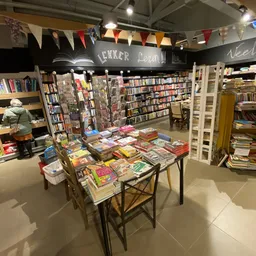 Tafels met uitgestalde tweedehands boeken en dvd's in de winkel, omgeven door kasten met verder aanbod