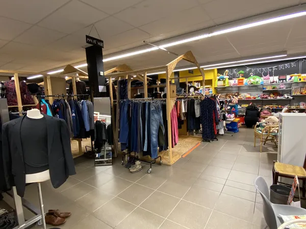 Winkelinterieur met kledingrekken, mannequins en spullen op stellingen