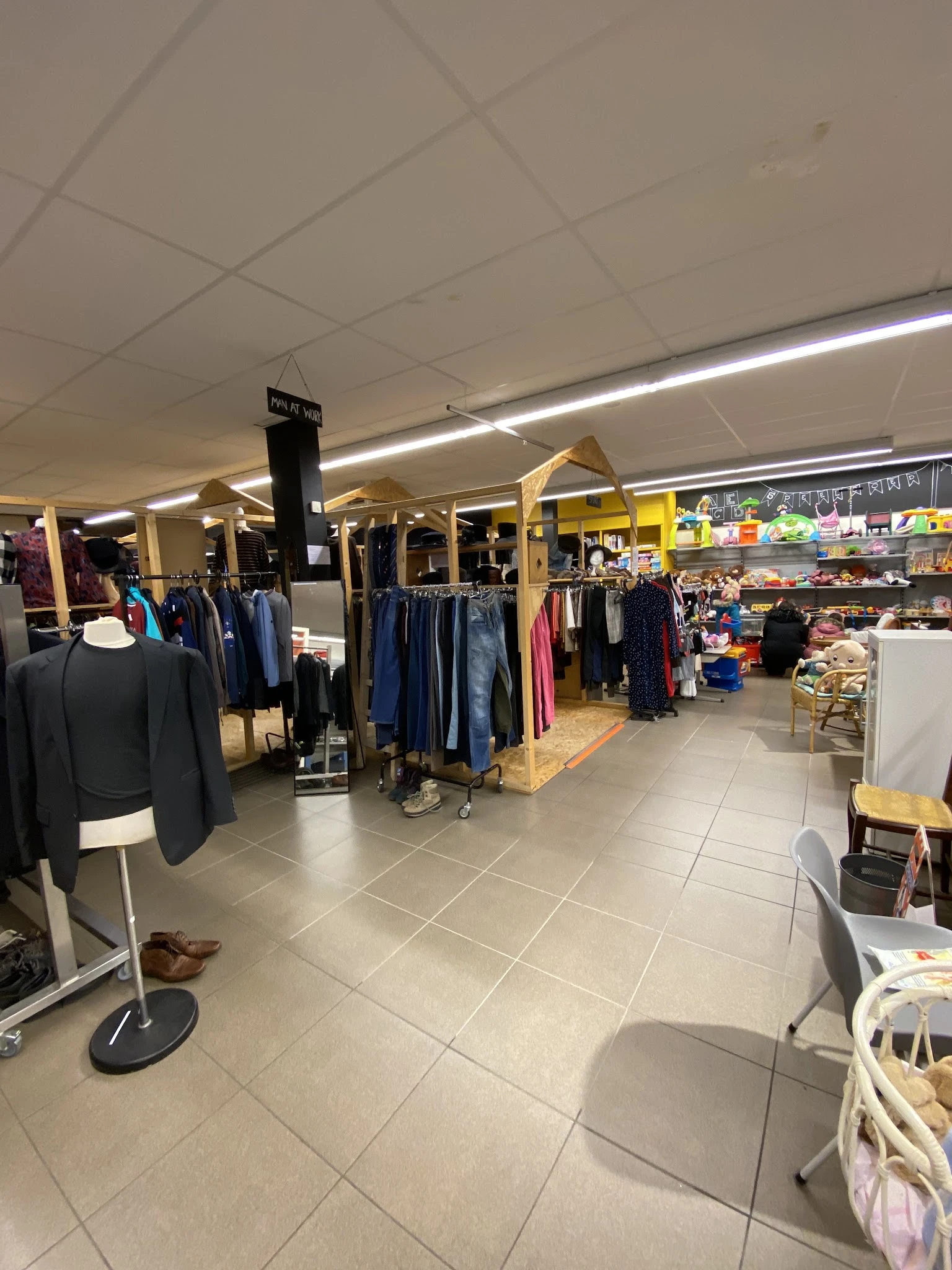 Winkelinterieur met kledingrekken, mannequins en spullen op stellingen