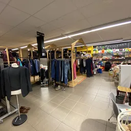 Winkelinterieur met kledingrekken, mannequins en spullen op stellingen