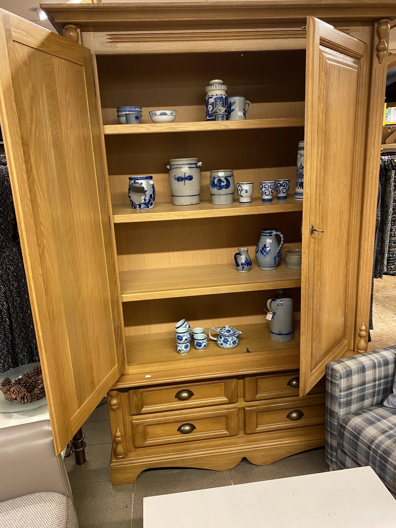 Houten kast met glazen deuren, gevuld met blauw-wit aardewerk en keramische huishoudartikelen