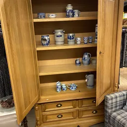 Houten kast met glazen deuren, gevuld met blauw-wit aardewerk en keramische huishoudartikelen
