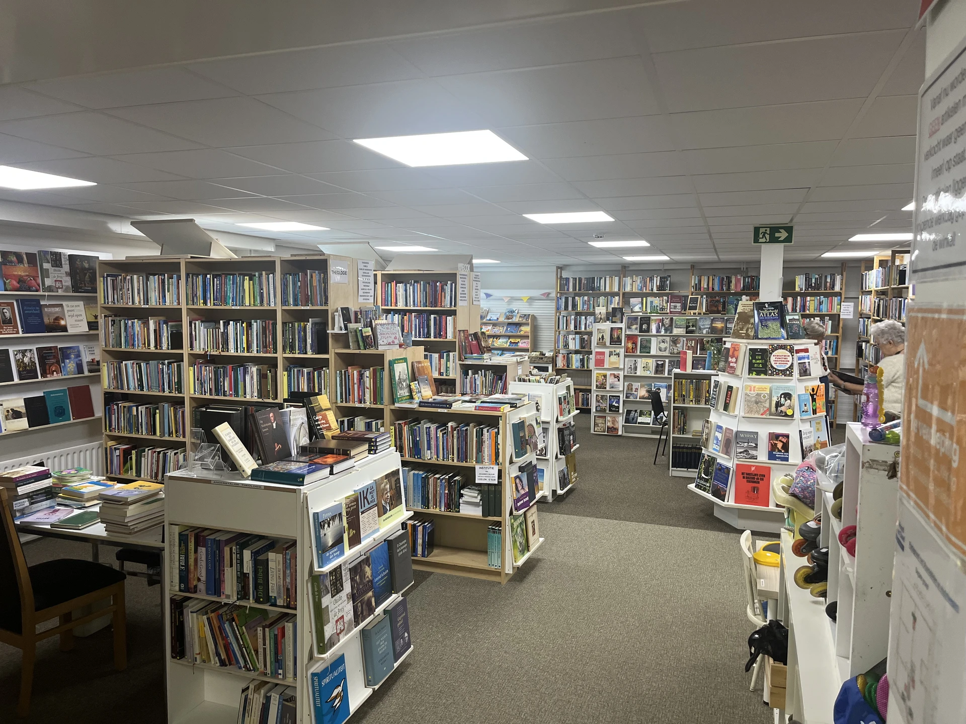 Winkelvloer met boeken in stellingen, leeshoek en diverse kasten vol tweedehands artikelen