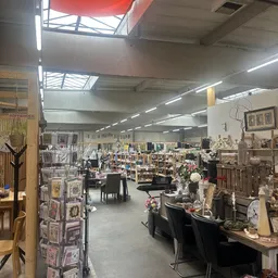 Overzicht van de winkelruimte met diverse meubels, decoratie en spullen uitgestald op rekken en tafels