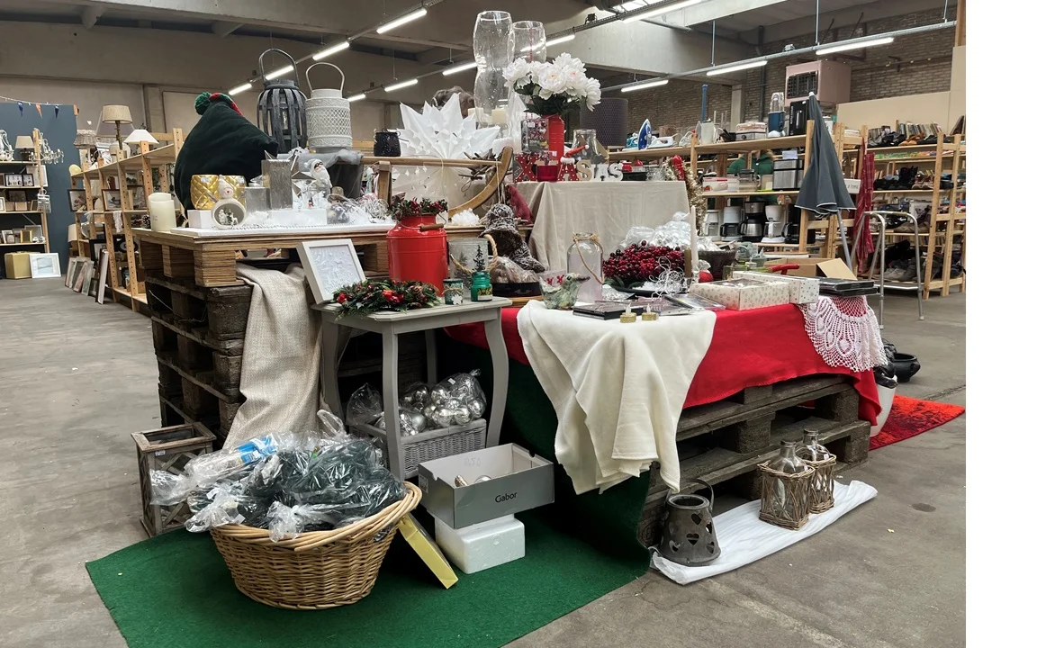 Winkelvloer met decoratieve display van kerstdecoraties, rode en witte stoffen, bloemen en seizoensartikelen op tafels