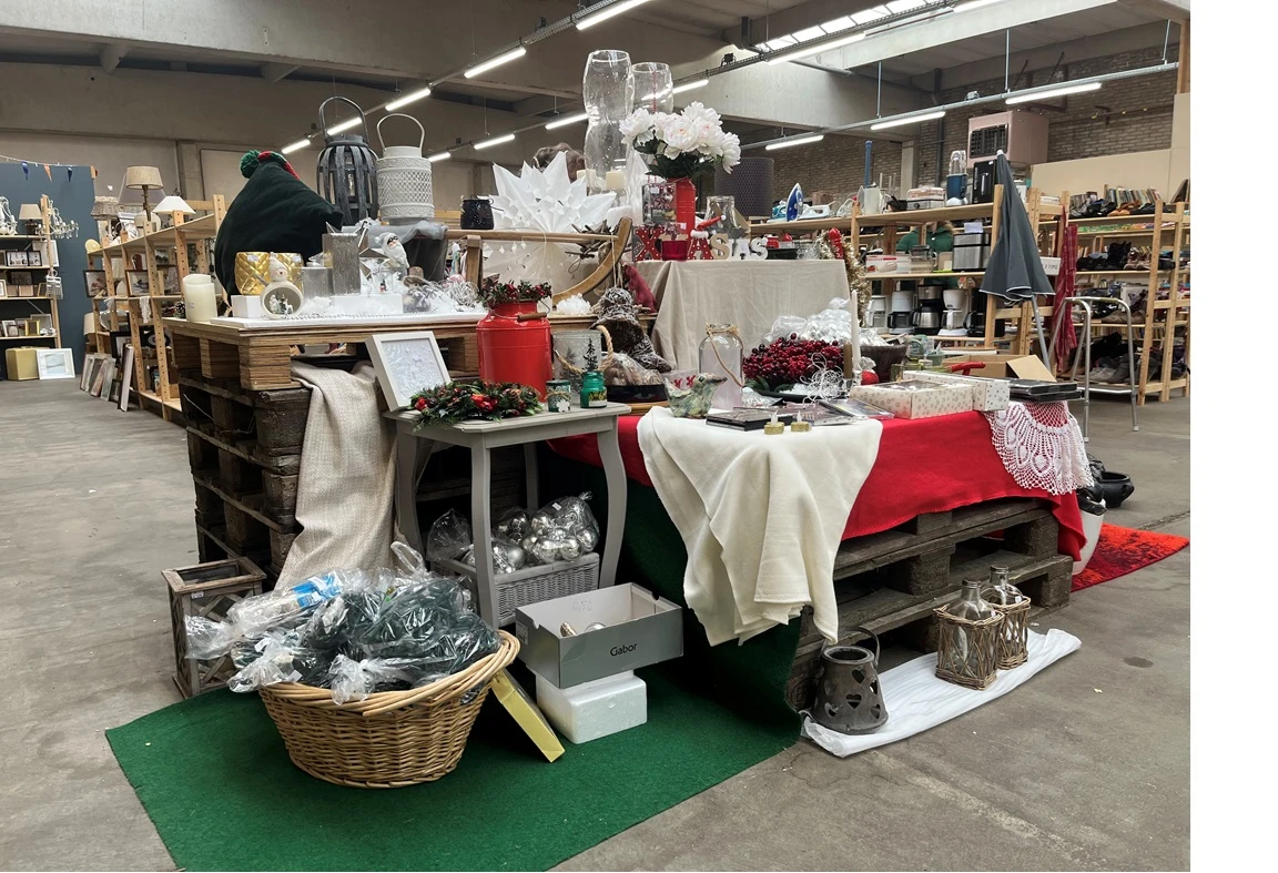 Winkelvloer met decoratieve display van kerstdecoraties, rode en witte stoffen, bloemen en seizoensartikelen op tafels