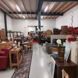 Ruim winkelinterieur met houten meubelen, zithoeken en diverse tweedehandsartikelen uitgestald