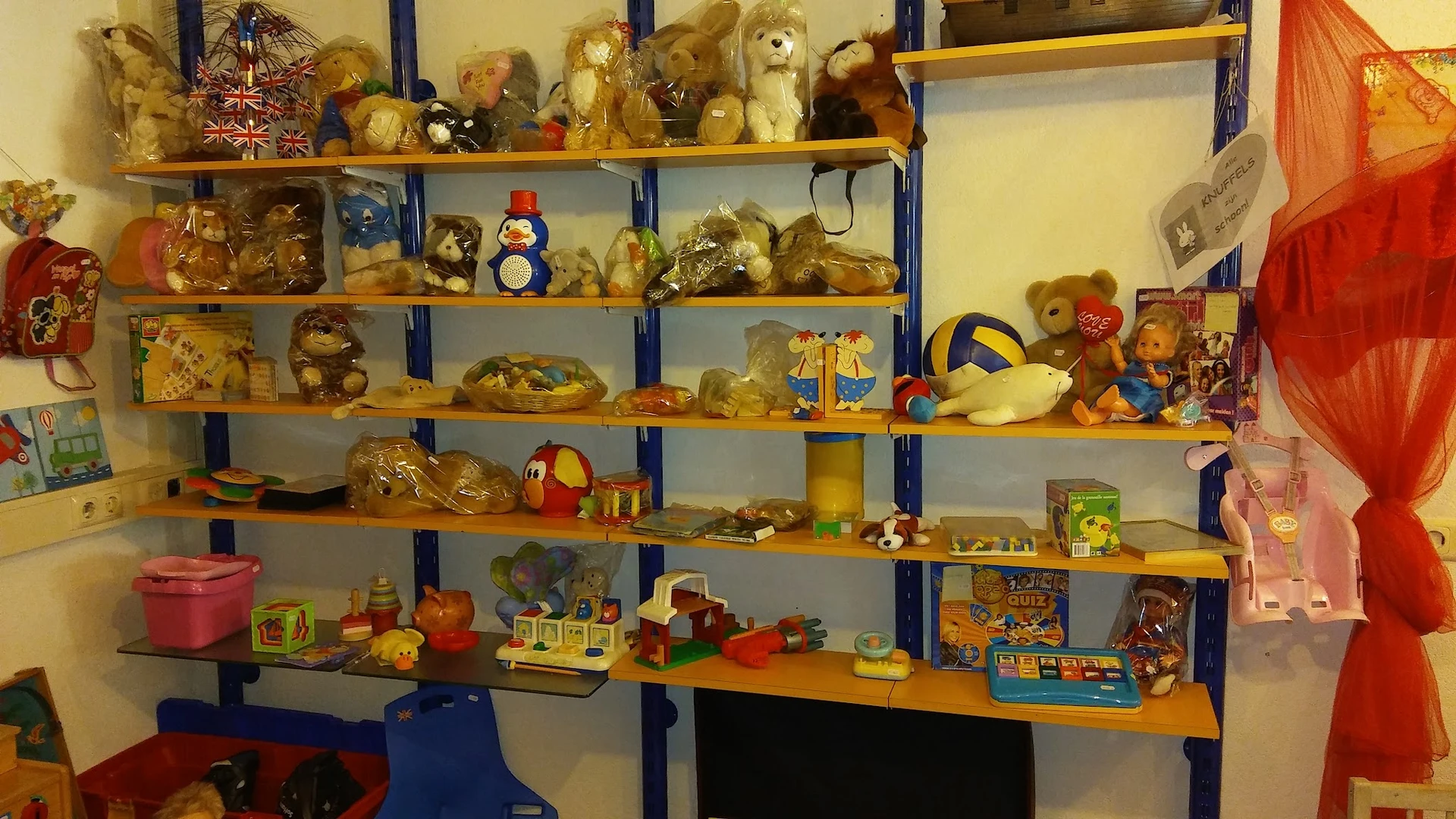 Stellingen gevuld met speelgoed, knuffels, decoratiefiguren en kinderspeelgoed in een kringloopwinkel