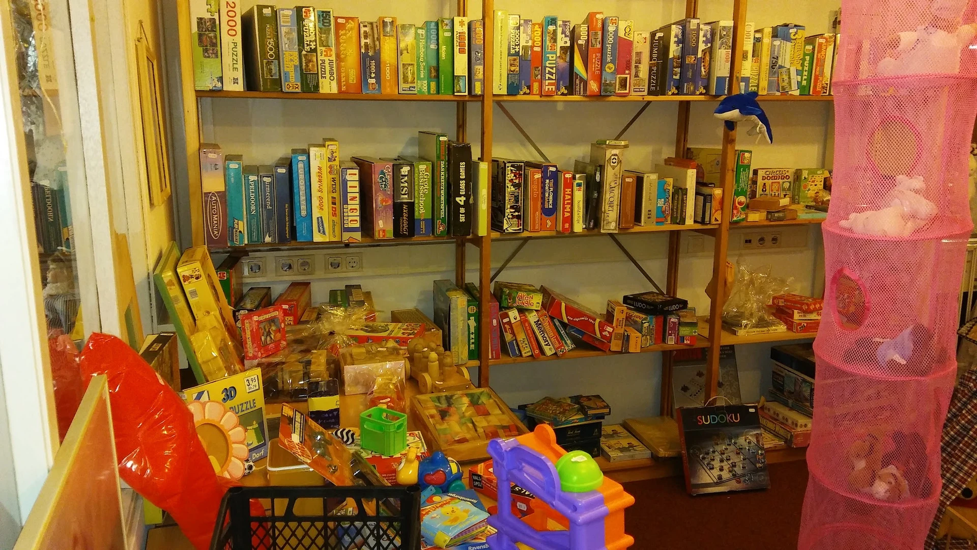 Boekenkasten met boeken en speelgoed, winkelvloer met speelgoedkratjes en kleurrijke items