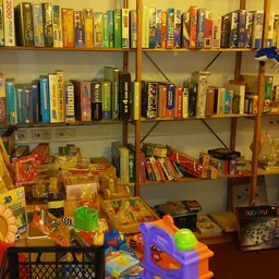 Boekenkasten met boeken en speelgoed, winkelvloer met speelgoedkratjes en kleurrijke items
