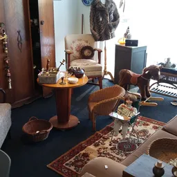 Interieur van kringloopwinkel met meubels, stoelen, tafels en huishoudelijke artikelen op blauwe vloer