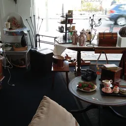 Interieur van kringloopwinkel met vintage meubels, decoratie en een uitgestalde tafel met eten